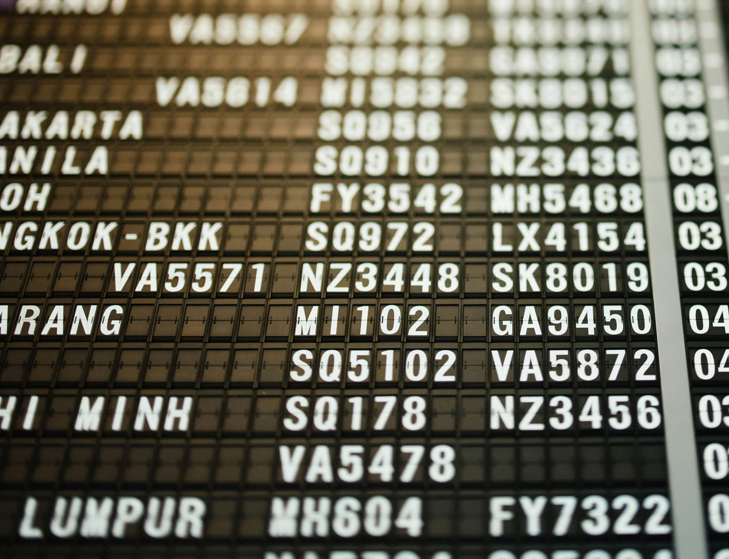An airport departure board, close up showing rows and rows of flight numbers